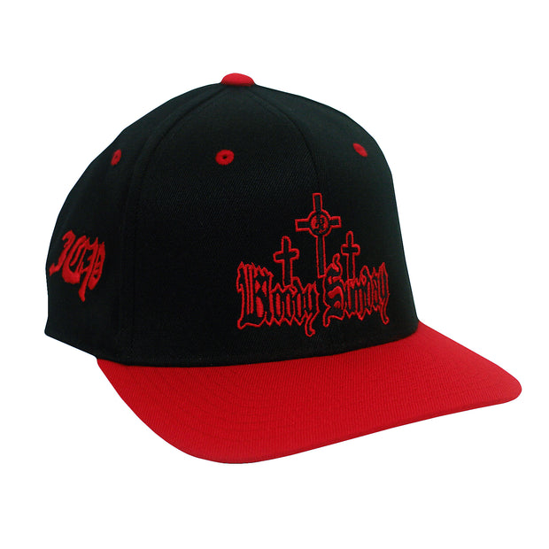 image of the front of a black snapback hat with a red bill. red embroidery on the left side that says I C P. the front has three crosses and says bloody sunday. 