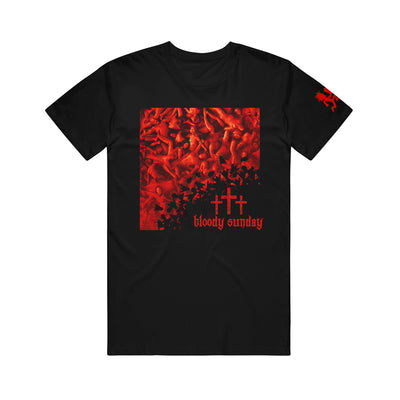 image of a black tee shirt on a white background. tee has center print of the bloody sunday album cover. cover has piles of red bodies and on the bottom right three crosses and says bloody sunday. red hatchetman logo on right sleeve
